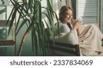 Small photo of Beautiful caucasian woman sipping morning coffee while concentrating reading a book in her living room. Lady studying textbook. Person spending time resting in