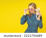 beautiful girl dressed in blue with pink sphynx cat on shoulder holding rose glasses with kiss on her lips, isolated on yellow background