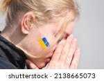 Portrait of Ukrainian teen blond hair girl with flag of Ukraine on cheek,patriotic symbol. Pray for Ukraine,war 2022 