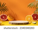 Empty wooden round podium on colorful yellow and orange background surrounded by citrus fruits. Display, pedestal for the presentation of cosmetic products, drinks