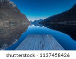 Small photo of Holy grail illustrated from Sognefjord or Sognefjorden created from mountain range with blue sky and reflection in clear water and having a wooden dock point out in a river in Flam