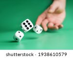 Hand throws dice on a green background with selective focus. Dice close up.