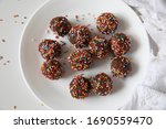 Delicious Candy sprinkle-Chocolate balls covered with colourful candies served in a white plate against white background. Copy space. Christmas, Indian burfi treat, healthy energising cookie concept
