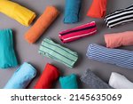 close up of rolled colorful t shirt clothes on gray table background, travel concept