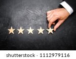 The businessman's hand in the suit holds the fifth star. Get the fifth star. The concept of the rating of hotels and restaurants, the evaluation of critics and visitors. Quality level, good service.