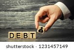 Small photo of Wooden blocks with the word debt and the image of dollars. Payment of taxes and of debt to the state. Concept of financial crisis and problems. Risk management. Debt exemption. loan