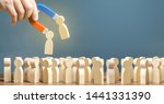 Small photo of Businessman with a magnet pulls wooden figures of people out of big crowd. Recruiting workers. Formation of a new team. Search for required people and workers with the necessary talents and skills