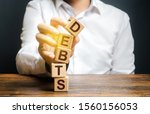 Small photo of A man breaks a tower of blocks with the word Debts. Reduction or restructuring of debt. Bankruptcy. Refusal to pay. Heavily indebted citizens low financial literacy. Get out of Debt