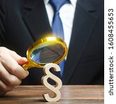 Small photo of A man examines a paragraph figure with a magnifying glass. Judicial practice. Legitimacy. Studying laws and legislation, norms, rules. Legal service, lawyer services. Protection of rights, interests.
