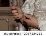 Small photo of The hands of the priest hold a brush with unctuous oil. The baptism ceremony. Close-up.