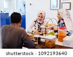 Small photo of A Muslim family sits down for a meal at home. Two women in head scarves and a man enjoy a quiet repast.