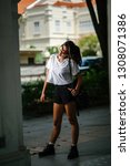 Small photo of Portrait of an unselfconscious, attractive and young Chinese Asian model girl smiling and goofing around as she poses for her photo on a street in Asia. She is tall, slim, cute and fashionable.