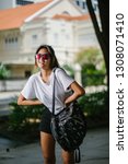 Small photo of Portrait of an unselfconscious, attractive and young Chinese Asian model girl smiling and goofing around as she poses for her photo on a street in Asia. She is tall, slim, cute and fashionable.