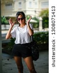 Small photo of Portrait of an unselfconscious, attractive and young Chinese Asian model girl smiling and goofing around as she poses for her photo on a street in Asia. She is tall, slim, cute and fashionable.