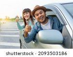 Small photo of Happy two young friends driver smiling while sitting in a car. Asian man and woman showing thump up and chreeful through window. Young couple wear hats driving car to travel on holiday vacation time.