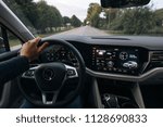 Man is driving a modern SUV car and holds a hand on the steering wheel. Driver goes fast on the city streets, from the first view  