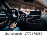Driving a car in the city. A man driving his modern sports car in the city center. A driver stuck in traffic. Modern car interior with big multimedia screen, sport steering wheel. Driver hold steering