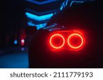 Supercar led taillight at the night city street, rear view close up red glow