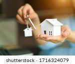 Woman holding white house model and house key in hand.Mortgage loan approval  home loan and insurance concept.