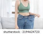 Small photo of Women show a reduced or thinned waistline, Losing weight and exercising can reduce belly fat and excess fat, Loosing weight by keeping diet, Loose jeans, Body slim, Thin waist wearing big.