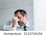 Business owner headache concept, businessman with painful migraine in office, selective focus