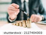 Investment return concept, businessman pointing to a coin stack at office desk, selective focus