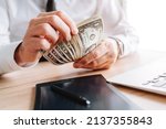 Small photo of Businessman counting petty cash US dollar banknotes in office, selective focus