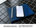 Small photo of Smartphone mockup with guestbook and pencil in apartment room