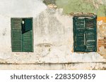 Small photo of Old timeworn windows with wooden shutters of an ruined house with damaged facade, copy space included