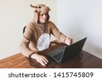 Office worker in cosplay costume of a cow. Guy in the funny animal pyjamas sleepwear near the laptop. Parody on manager.