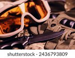 Tactical military gloves, helmet, glasses and knife on the khaki camouflage uniform. Soldier ammunition.