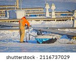 Small photo of An ice fisherman drilling a hole with an augur close to a pier. Small Boat Harbor. Buffalo, New York, USA, January 31st, 2022