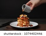 Woman pouring maple syrup on tasty pancakes