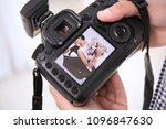 Professional photographer holding camera with lovely wedding couple on display, closeup