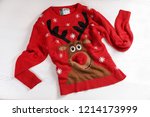 Christmas sweater with pattern on wooden background, top view