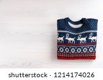 Christmas sweater with pattern and space for text on wooden background, top view