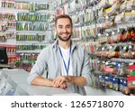 Salesman standing near showcase with fishing equipment in sports shop