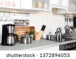 Different appliances, clean dishes and utensils on kitchen counter