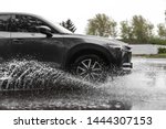 Small photo of Modern car driving outdoors on rainy day