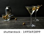 Glasses of Classic Dry Martini with olives on grey table against black background