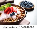 Delicious yogurt with granola and berries served on grey table, closeup