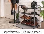 Shelving rack with stylish shoes and accessories near white brick wall indoors