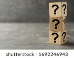 Wooden cubes with question marks on grey stone table. Space for text