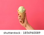 Woman holding waffle cone with delicious ice cream on pink background, closeup
