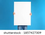 Man holding blank poster on blue background