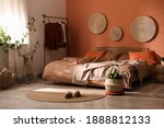 Bed with orange and brown linens in stylish room interior