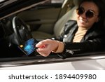 Woman sitting in car and giving credit card at gas station, focus on hand