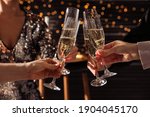 People clinking glasses of champagne indoors, closeup