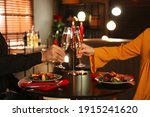 Couple clinking glasses of champagne at romantic dinner in restaurant, closeup