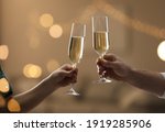 People clinking glasses of champagne against blurred background, closeup. Bokeh effect